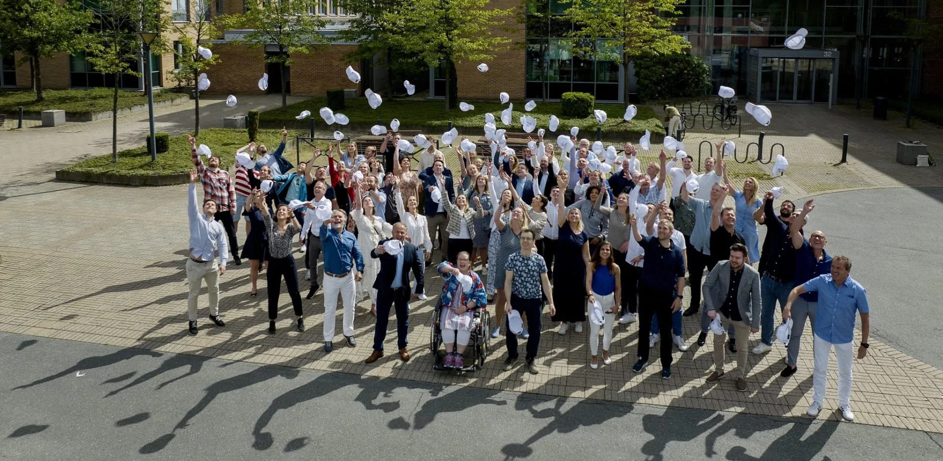 Glade medarbejdere i Xledger fejrer succes og kaster huerne i vejret. Foto