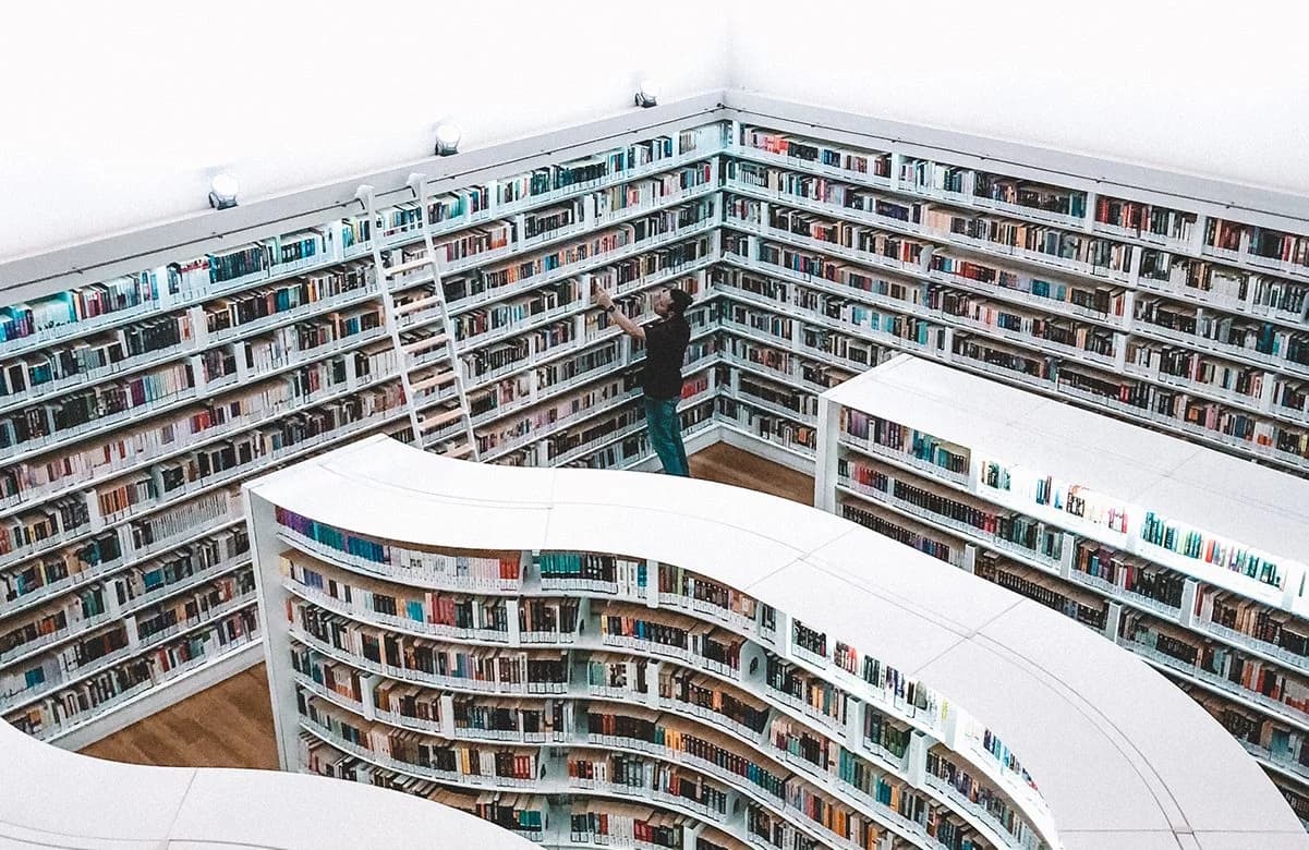 En mann solterer bøker på et bibliotek. Foto