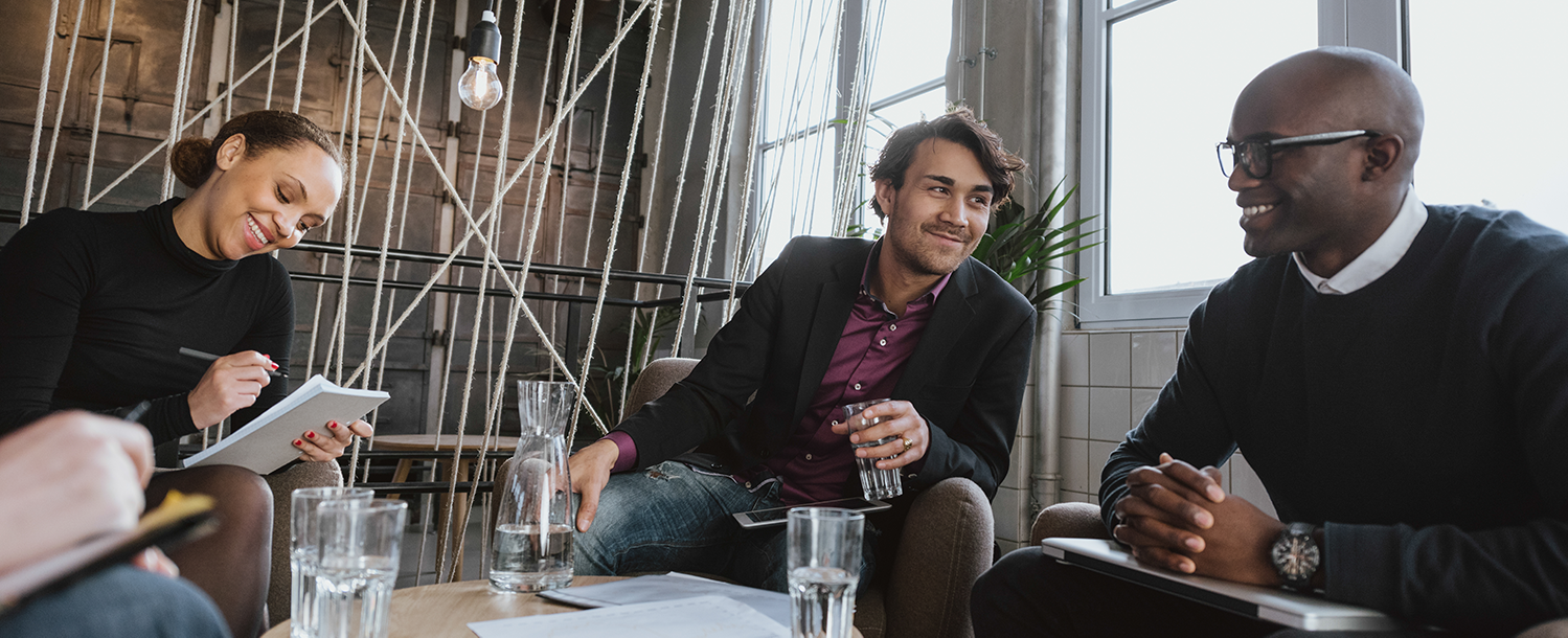 Tre personer som sitter sammen og snakker. Foto