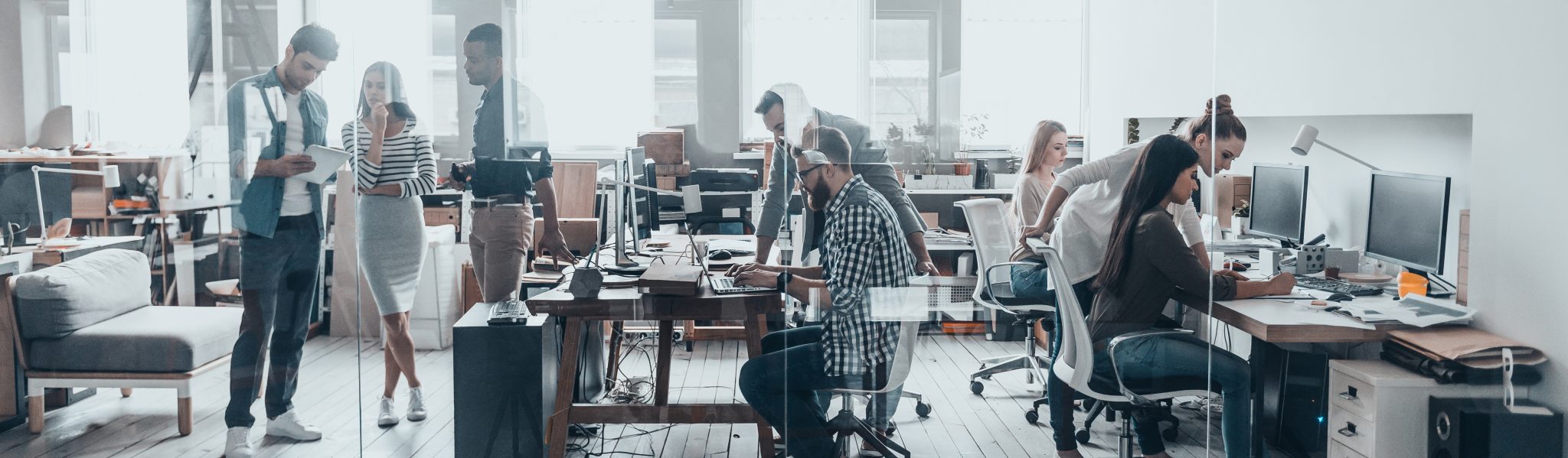 A busy and vibrant office setting with workers at desks and in discussions.