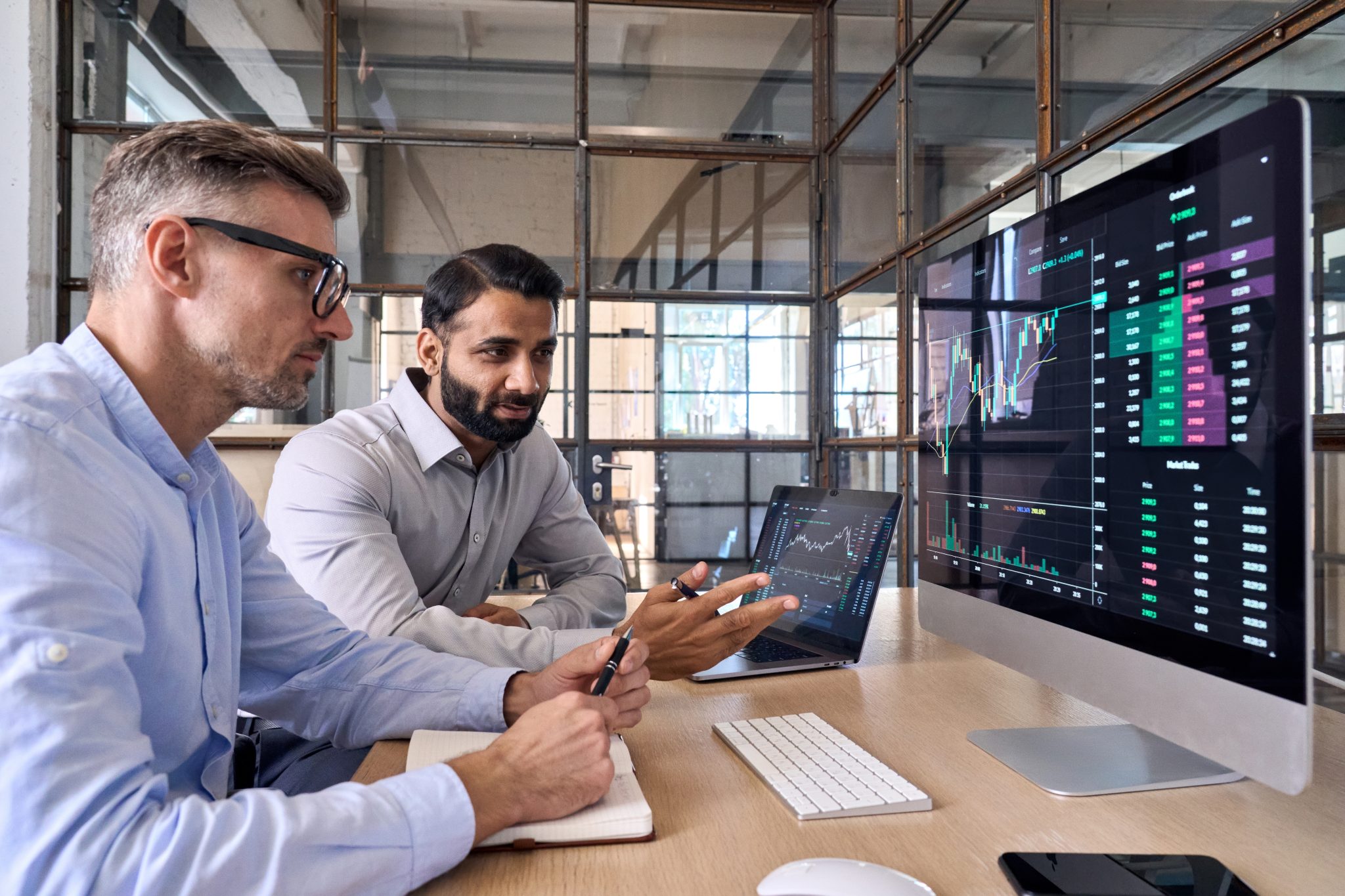 Two accountants talking over data and a laptop in a brightly lit meeting room