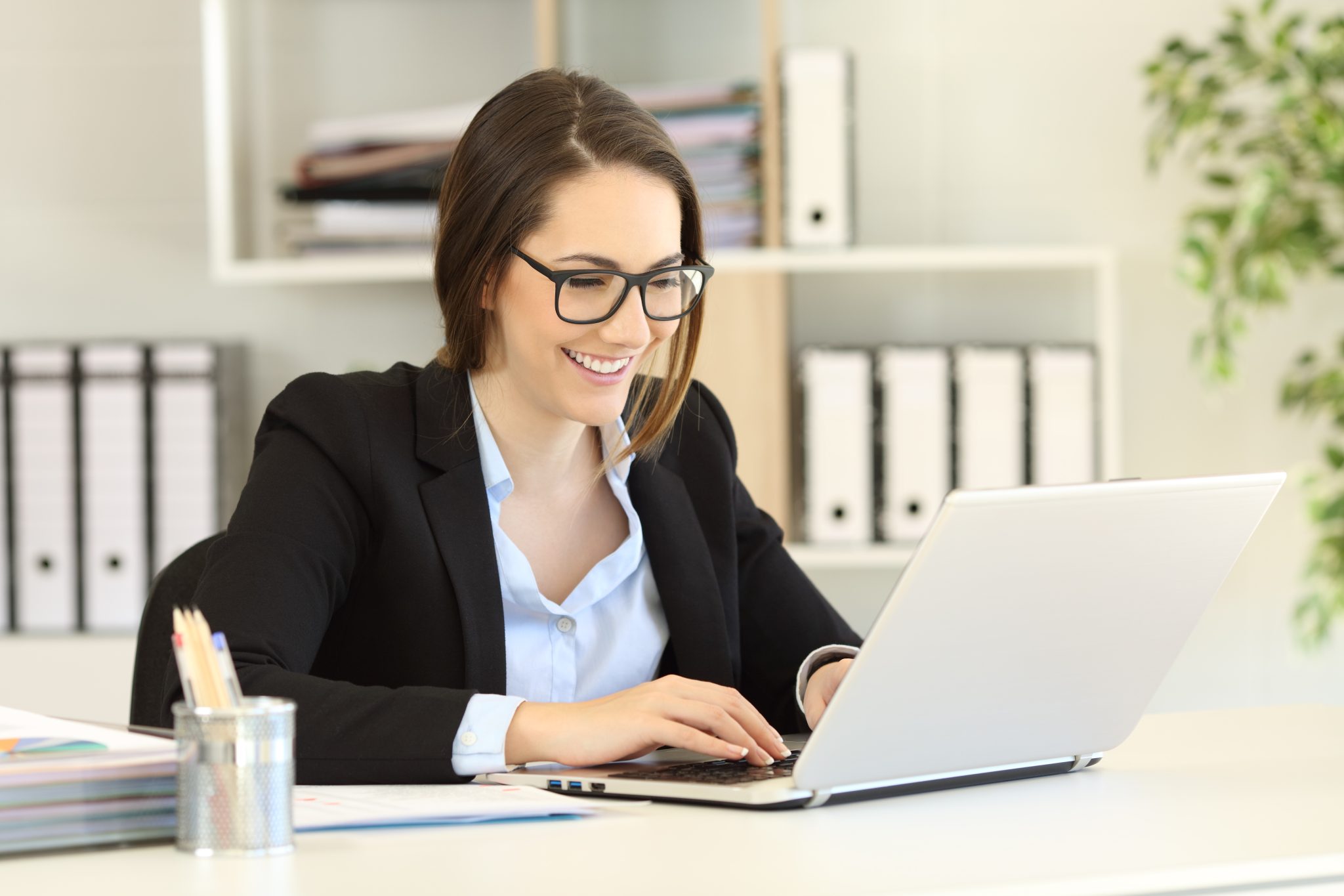Smartly dressed female accountant working in a bright meeting room on laptop