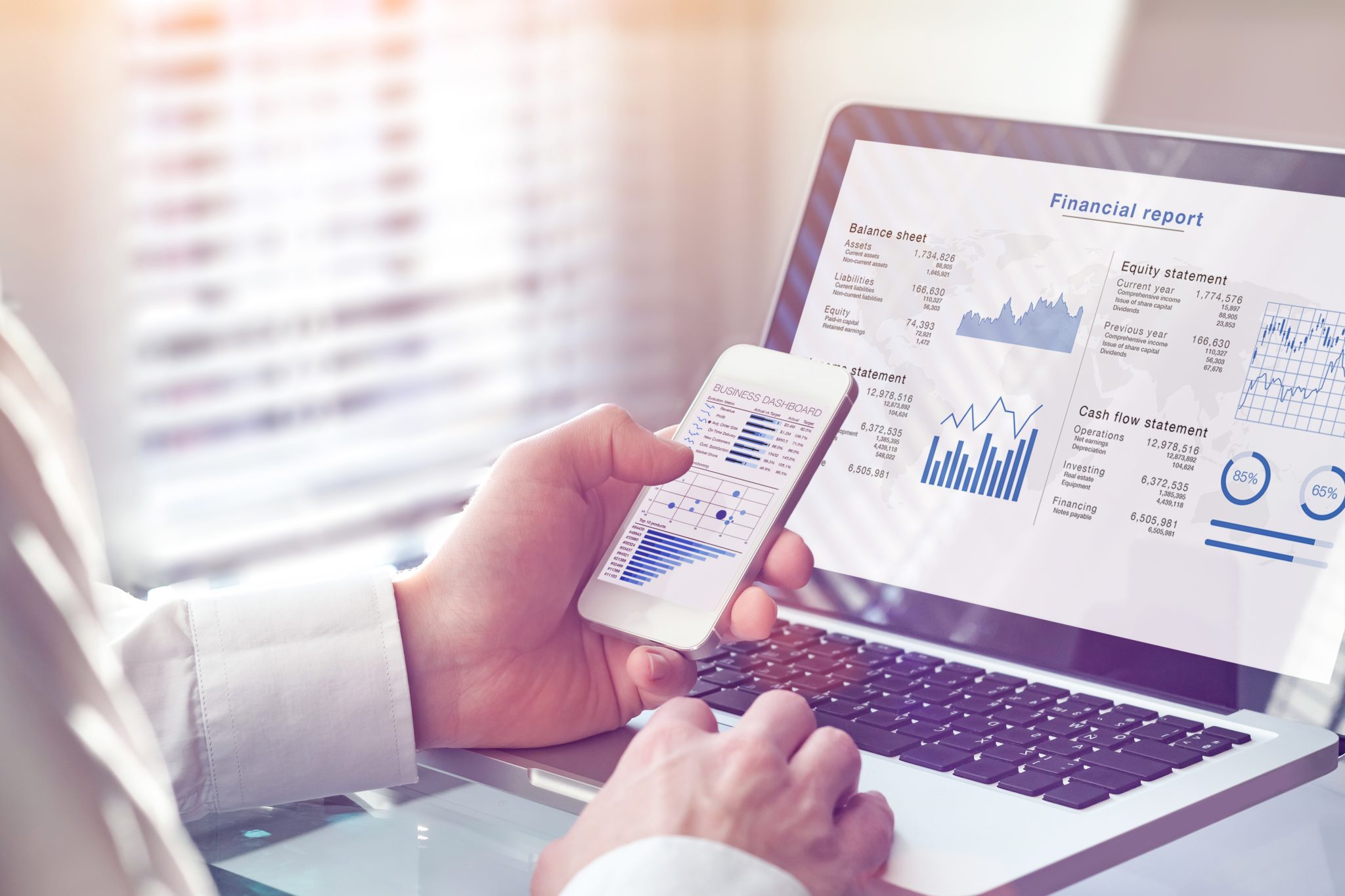 Man looking at data on laptop and mobile phone