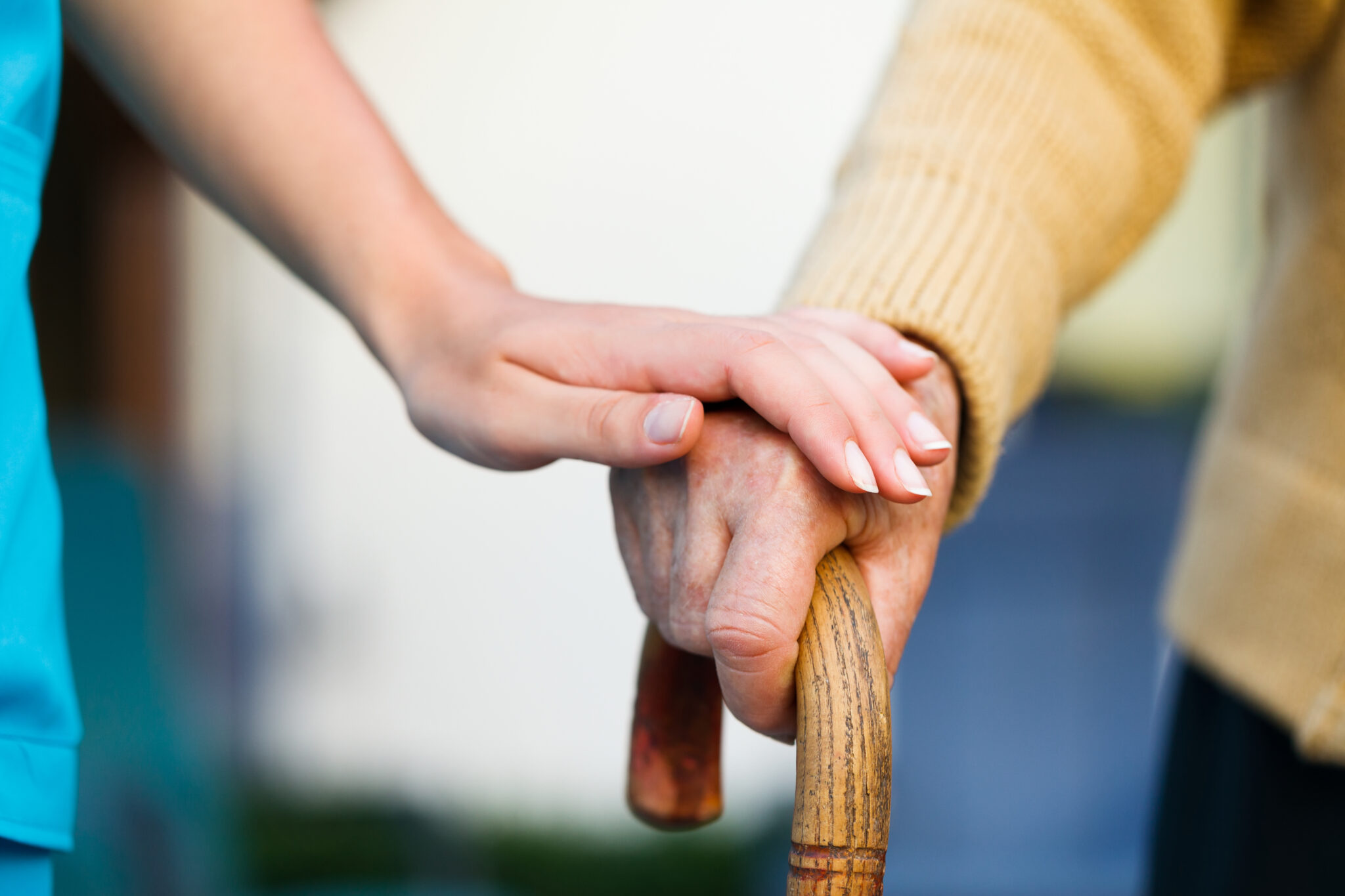 Doctor holding a senior patients 's hand on a walking stick - special medical care concept for Alzheimer 's syndrome.