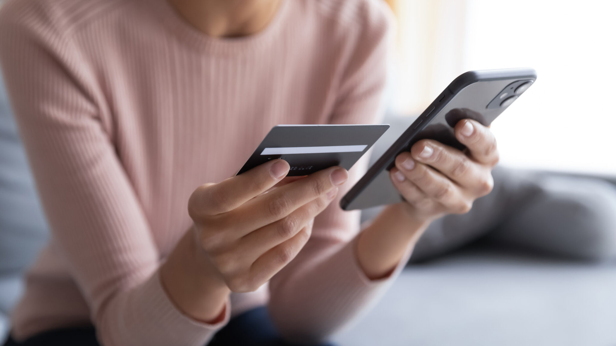 Close up of females hands holding a smart phone and bank card