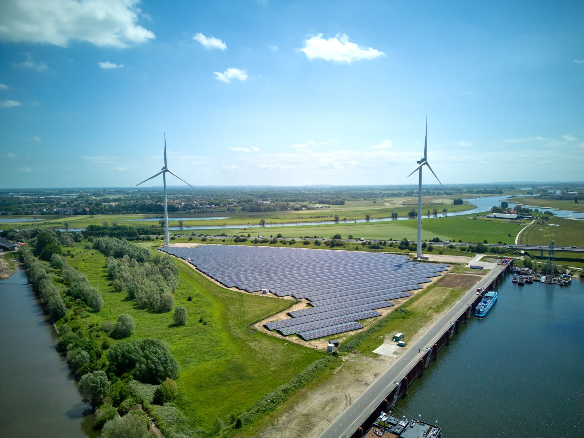 Drone aerial shot of Dutch windmill wind turbine and solar panels for renewable and sustainable clean energy close to highway and river in the background
