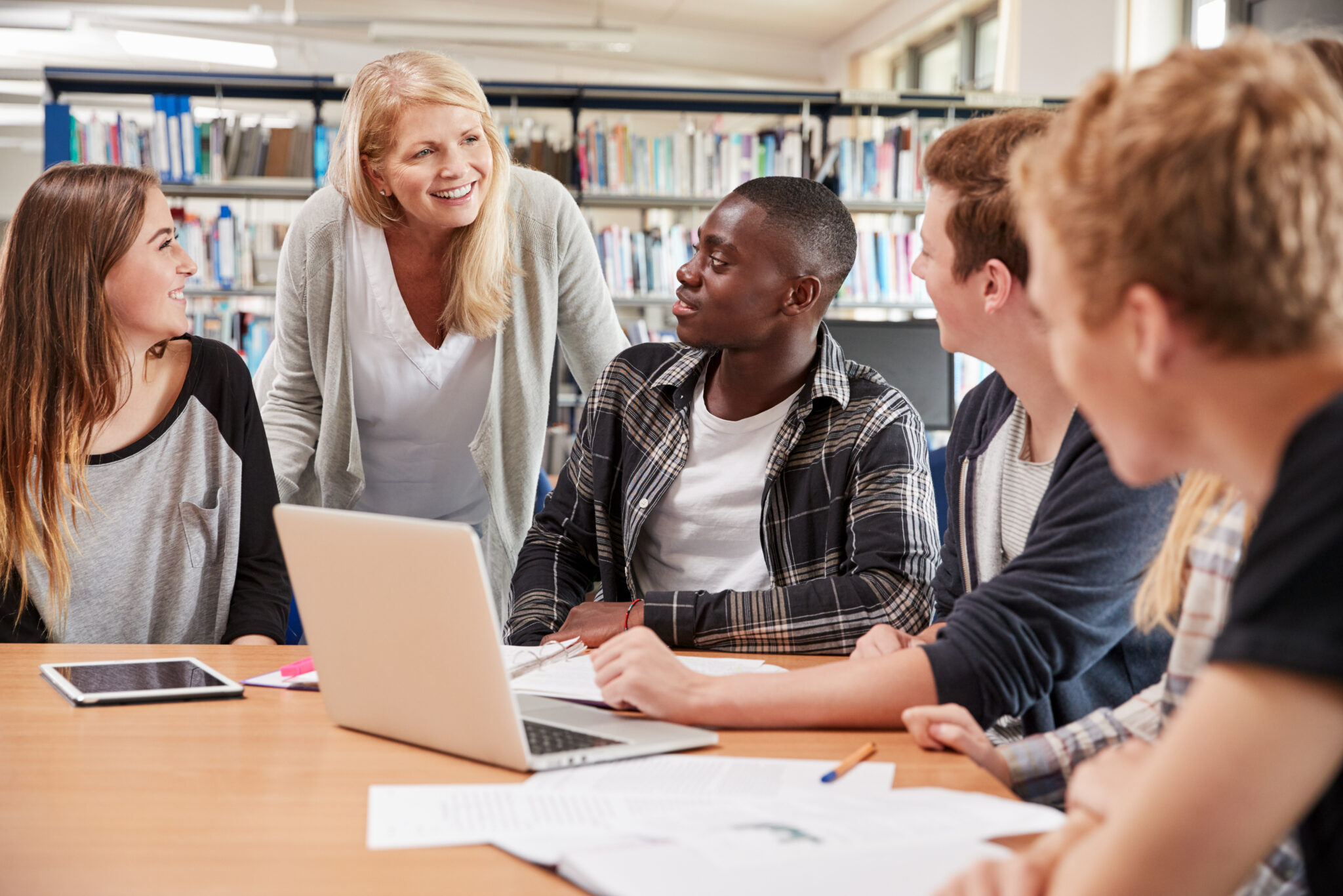 Female Teacher Working With College Students In Library