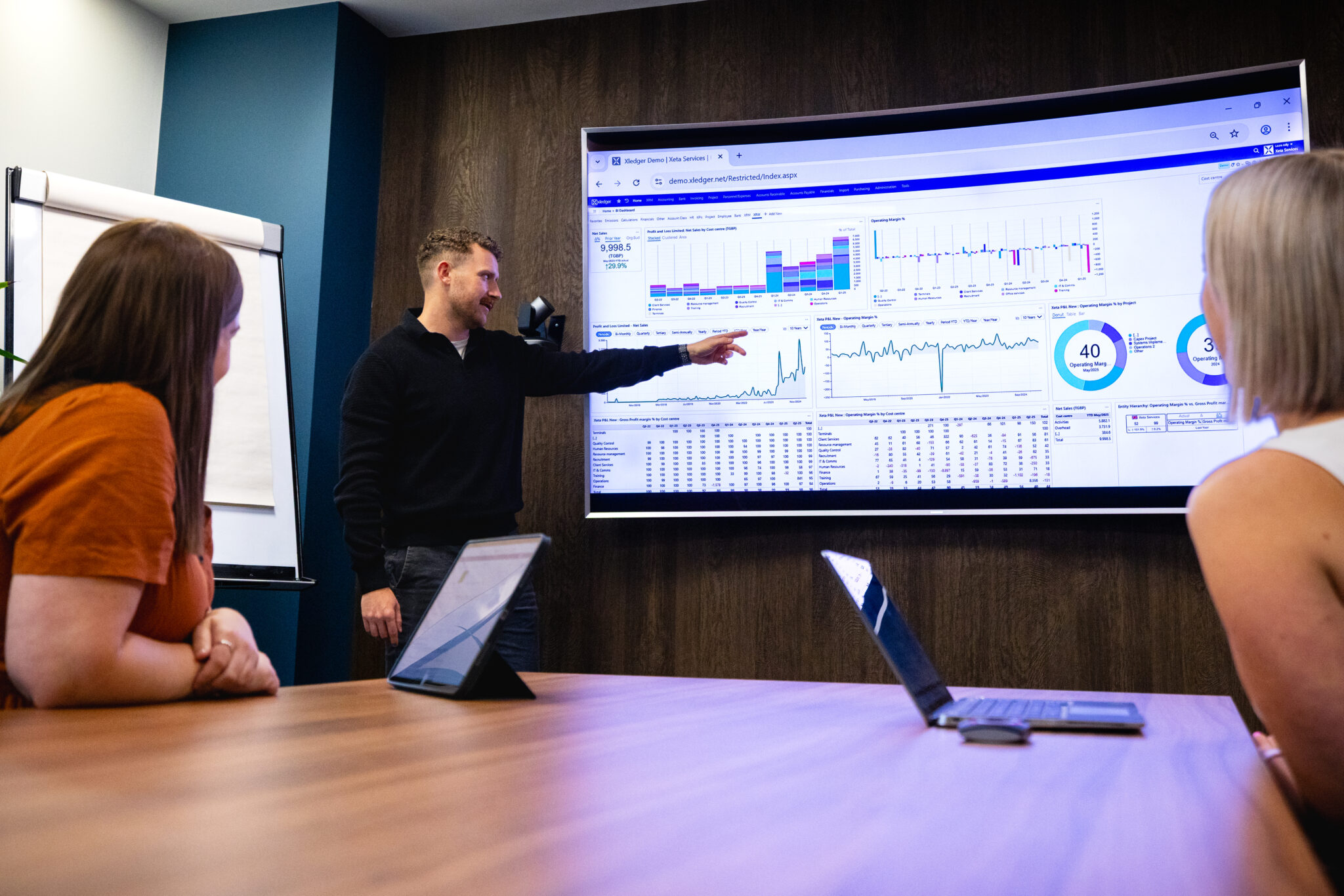 Man presenting Xledger's software on screen to people