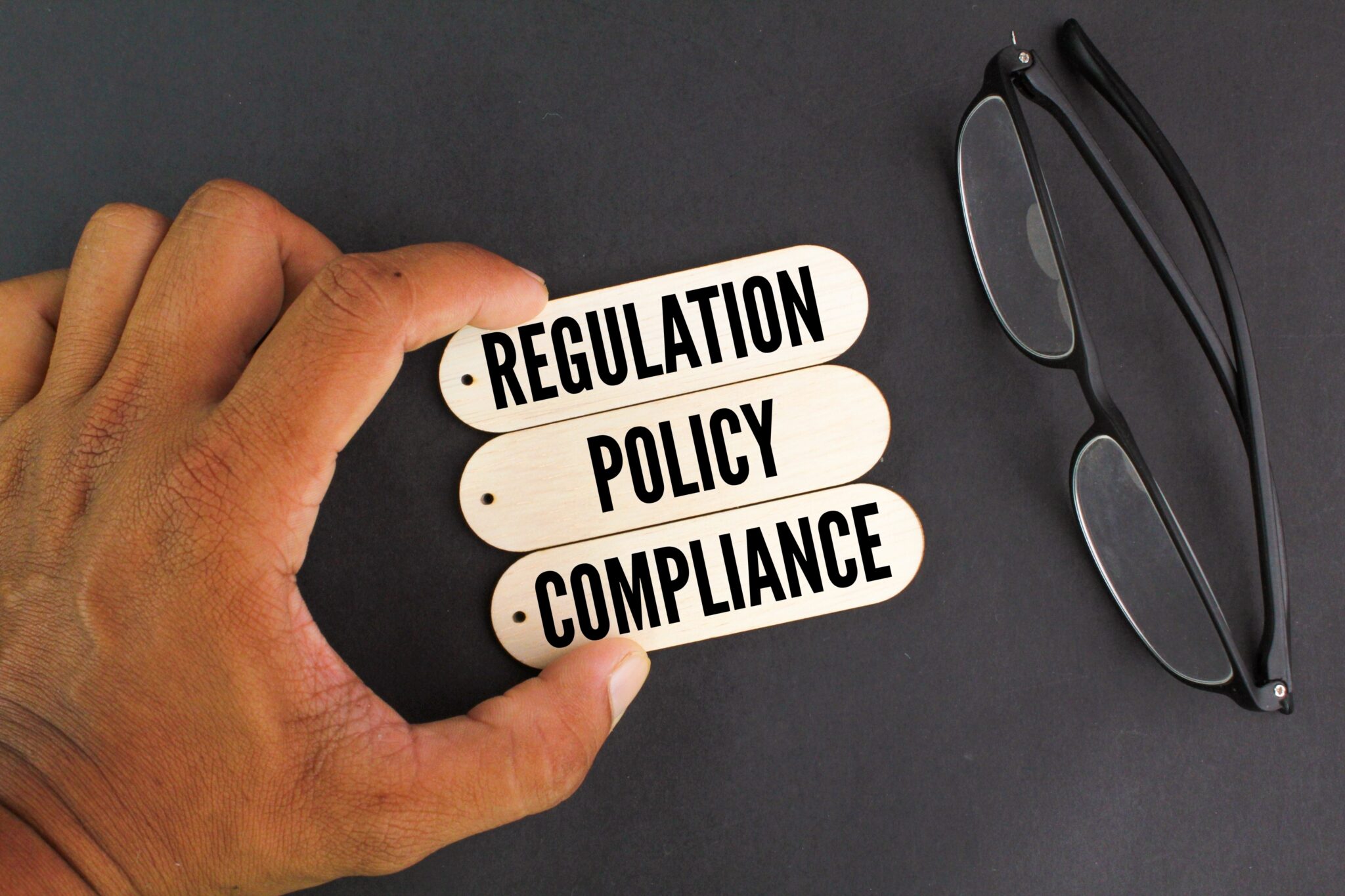 Hand,Holding,A,Stick,With,The,Three,Words,Regulation,,Policy