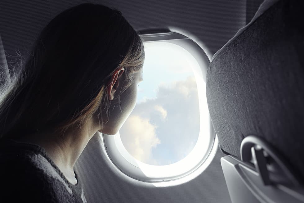 Passenger looking out of an airplane window during a flight.