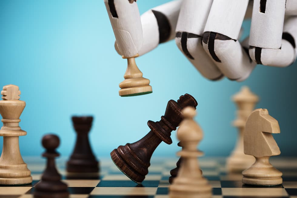 A robotic hand moves a white chess piece on a chessboard, toppling a black king, symbolizing artificial intelligence defeating a human opponent.