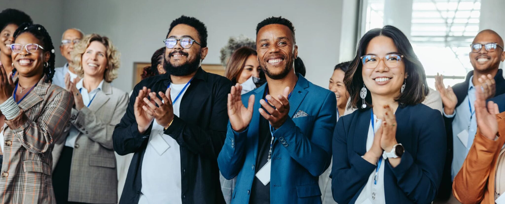 Diverse group of business professionals applauding during a meeting or presentation in a modern office.