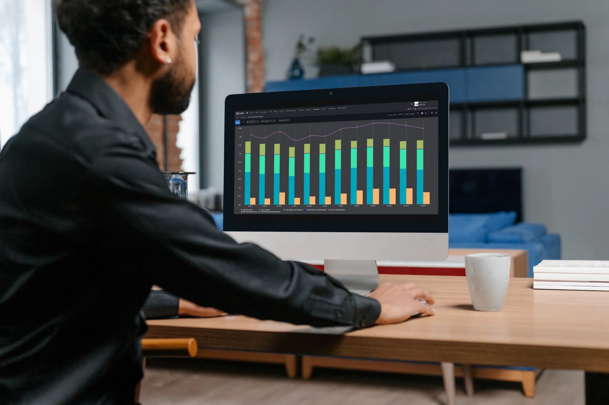 Person analyzing data on a desktop computer with charts displayed on the screen