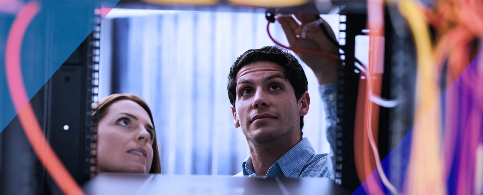 Two people working on network cables inside a server rack