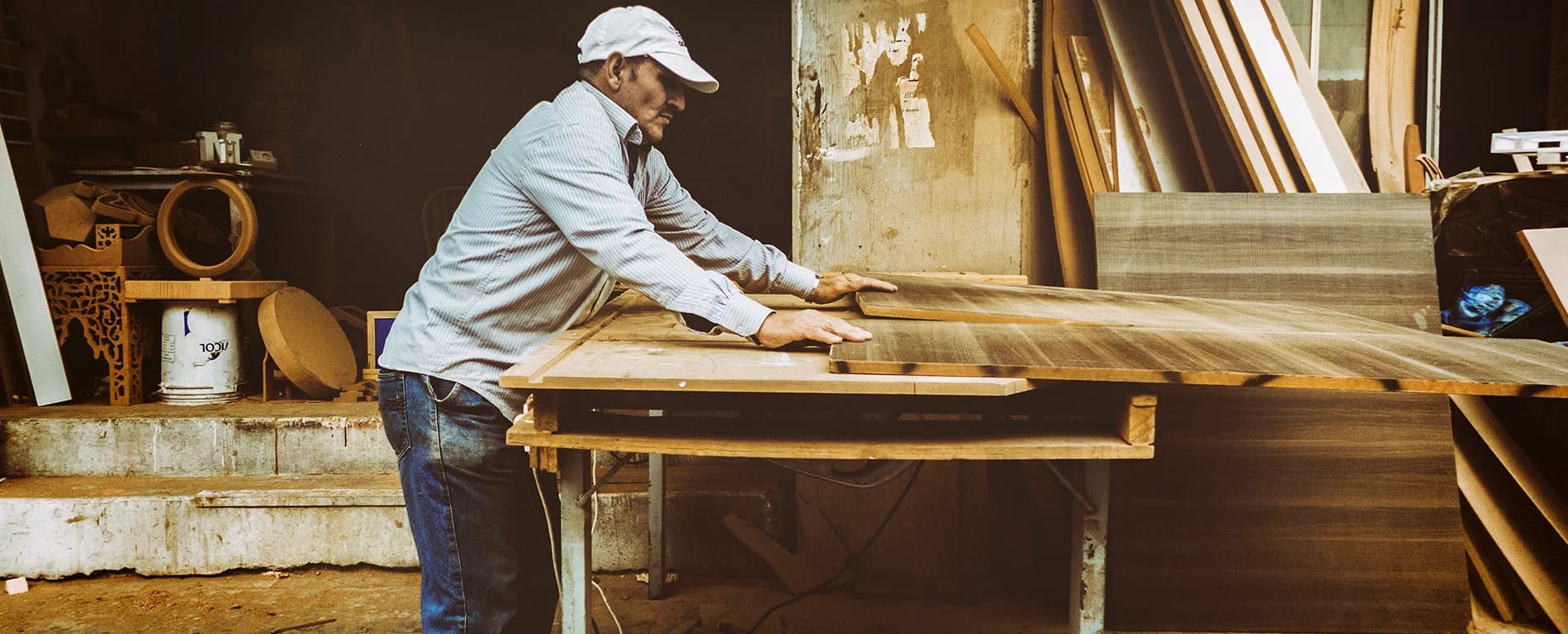 Man cutting a wooden board in a workshop with woodworking tools