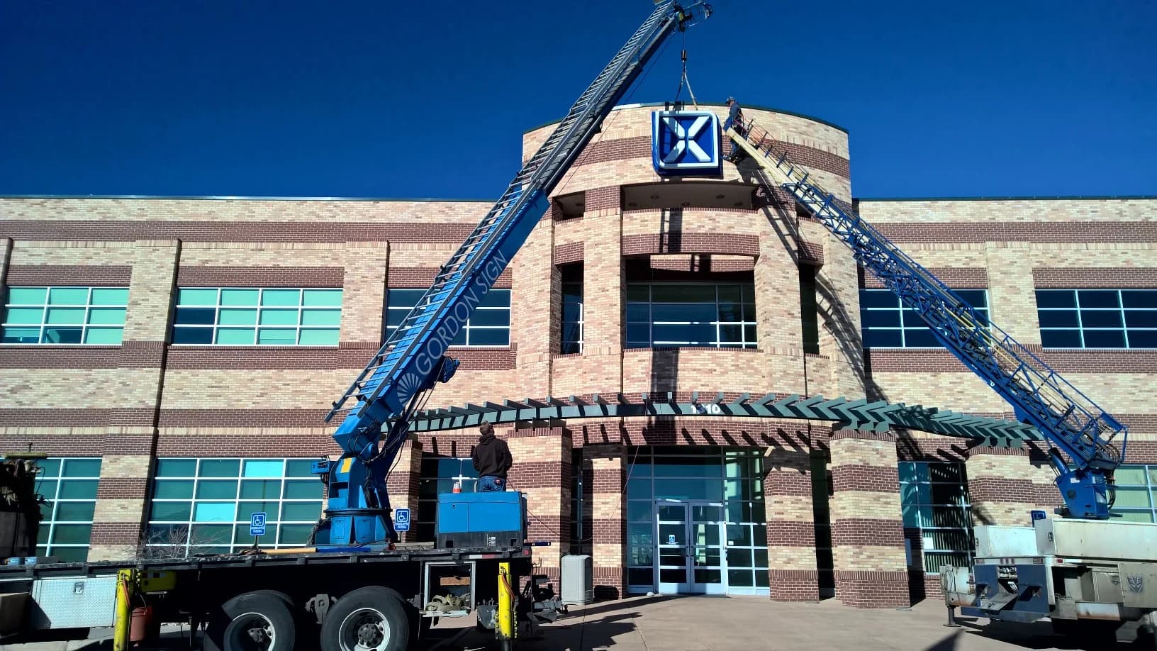 Crane installing Xledger sign on office building facade