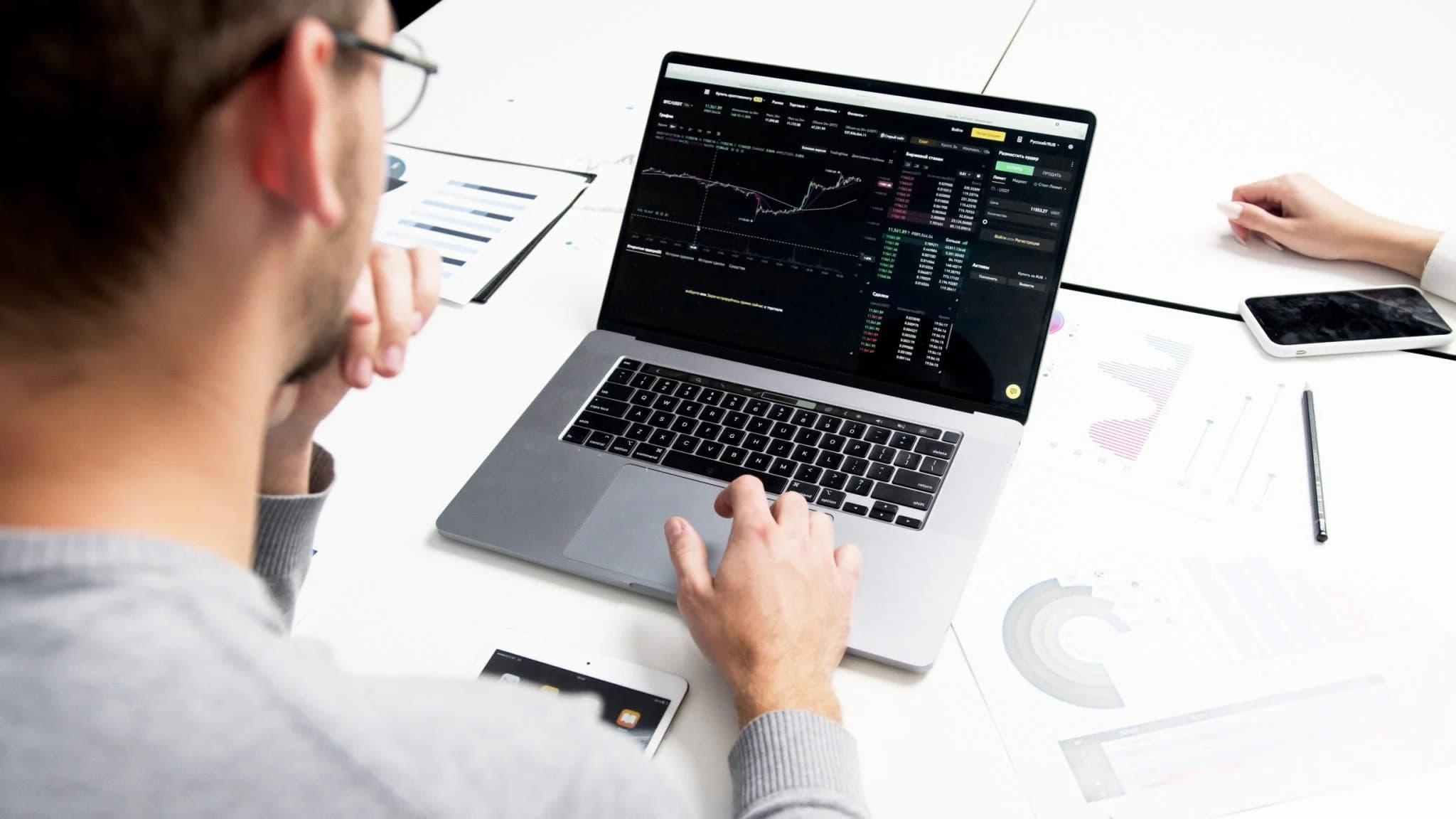 Person analyzing financial charts on a laptop with reports on the desk