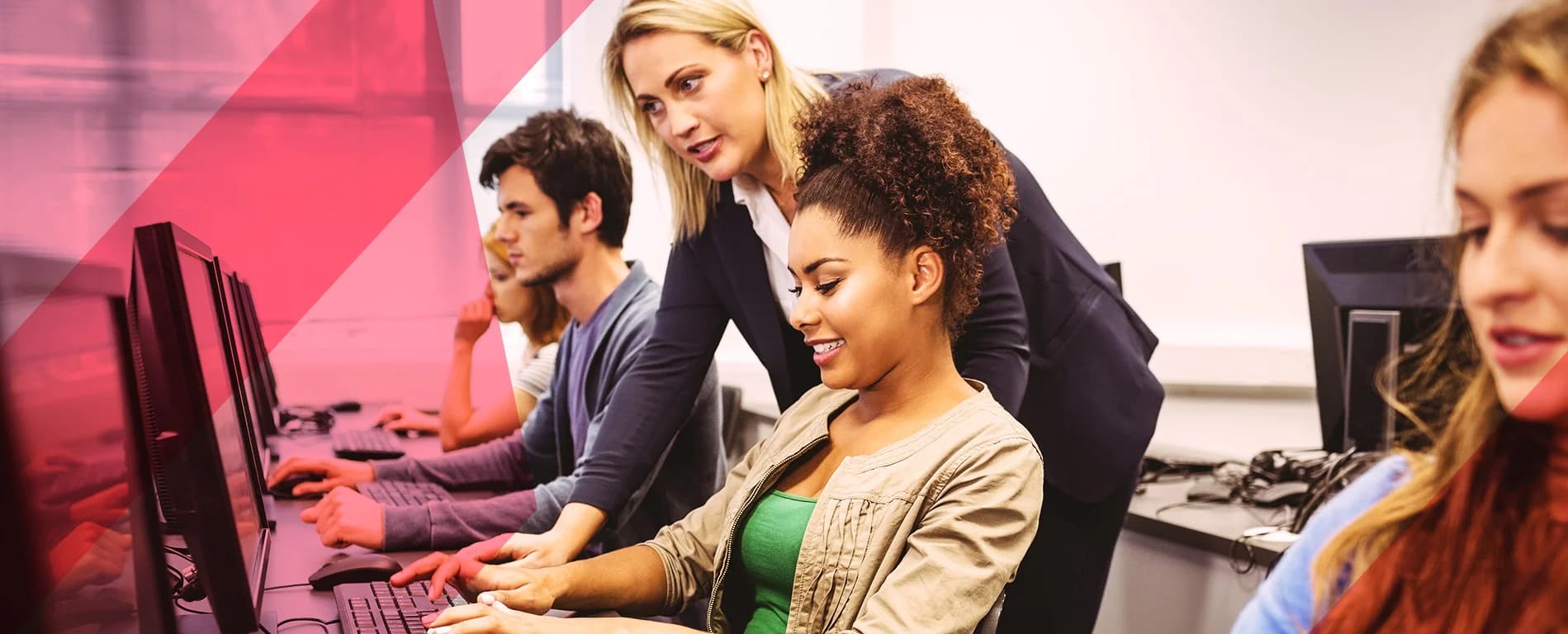 Instructor assisting students working on computers in a classroom