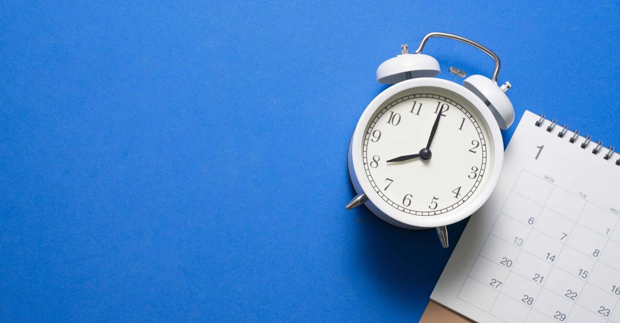 Alarm clock next to a calendar on a blue background