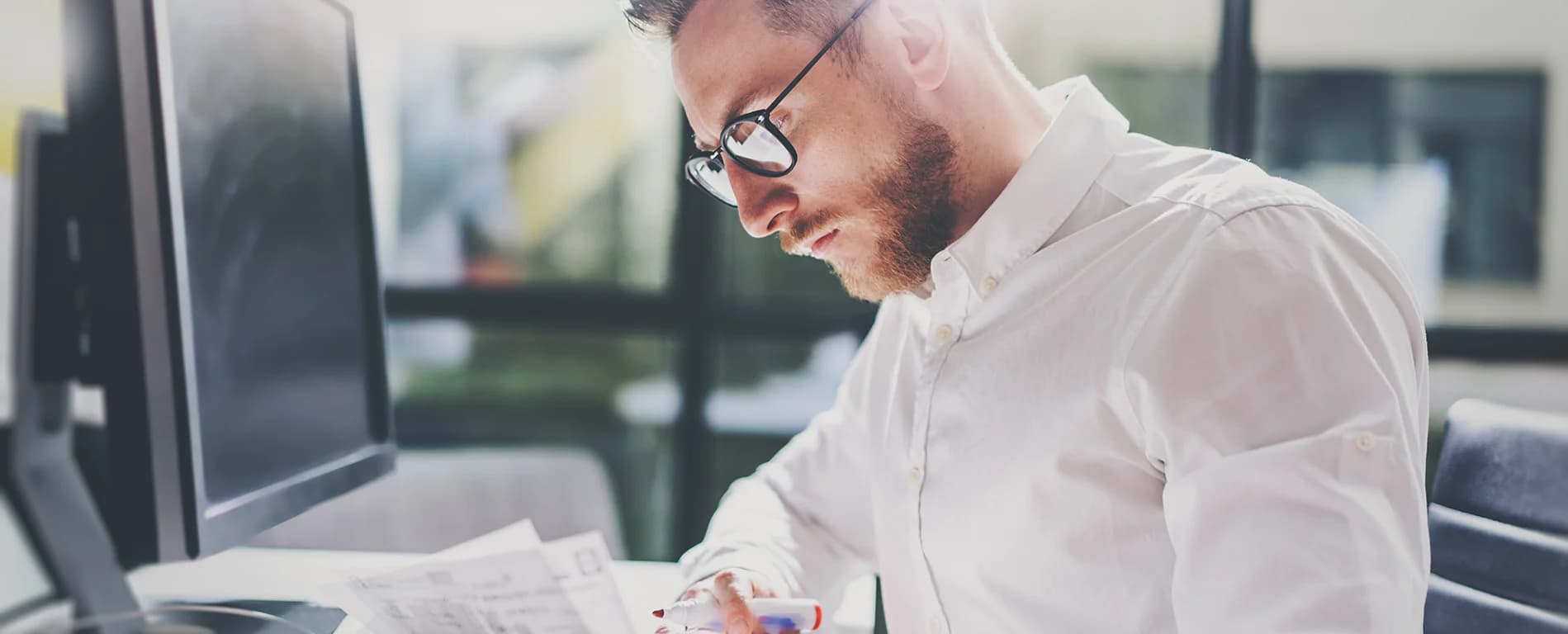 Man reviewing documents and working at a computer desk