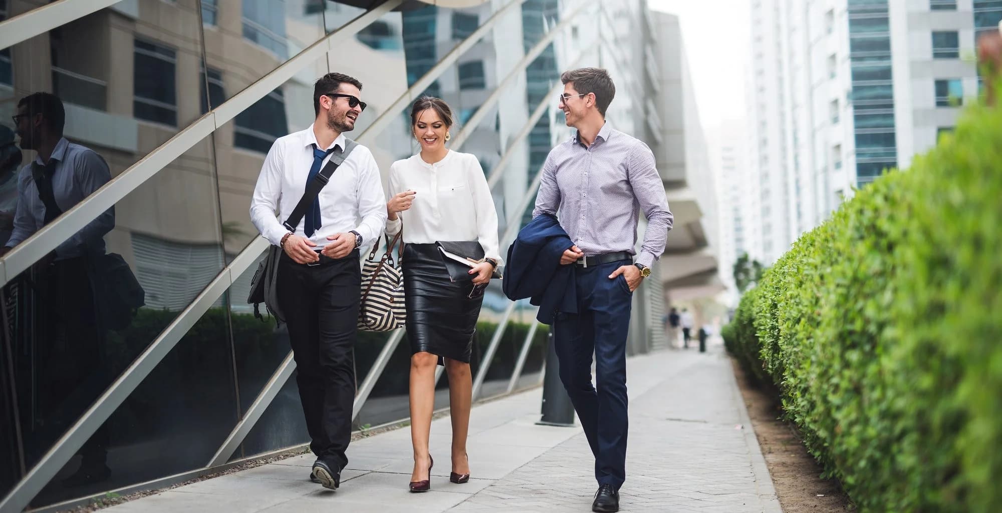 Three business professionals walking and talking outside an office building.
