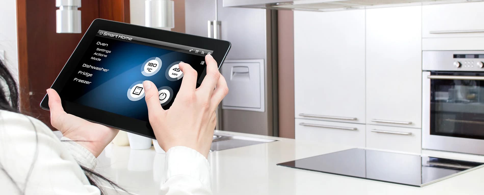 Person controlling smart home appliances on a tablet in a modern kitchen.