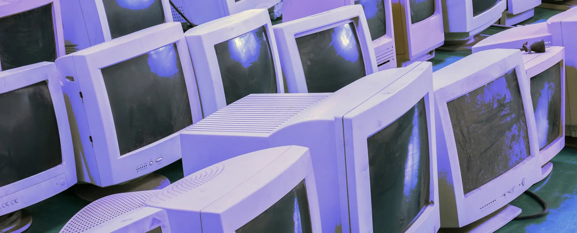 Stack of old CRT computer monitors piled together in a room