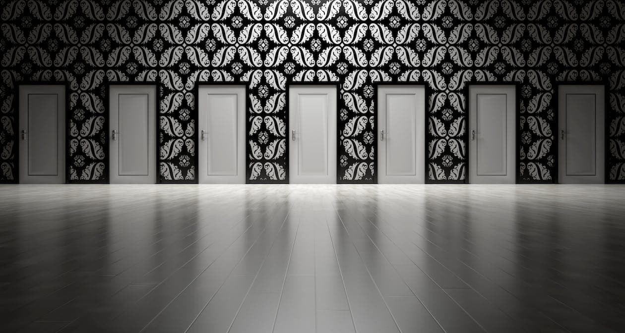 Row of identical closed doors along a patterned wall in an empty room, symbolizing multiple choices or opportunities.
