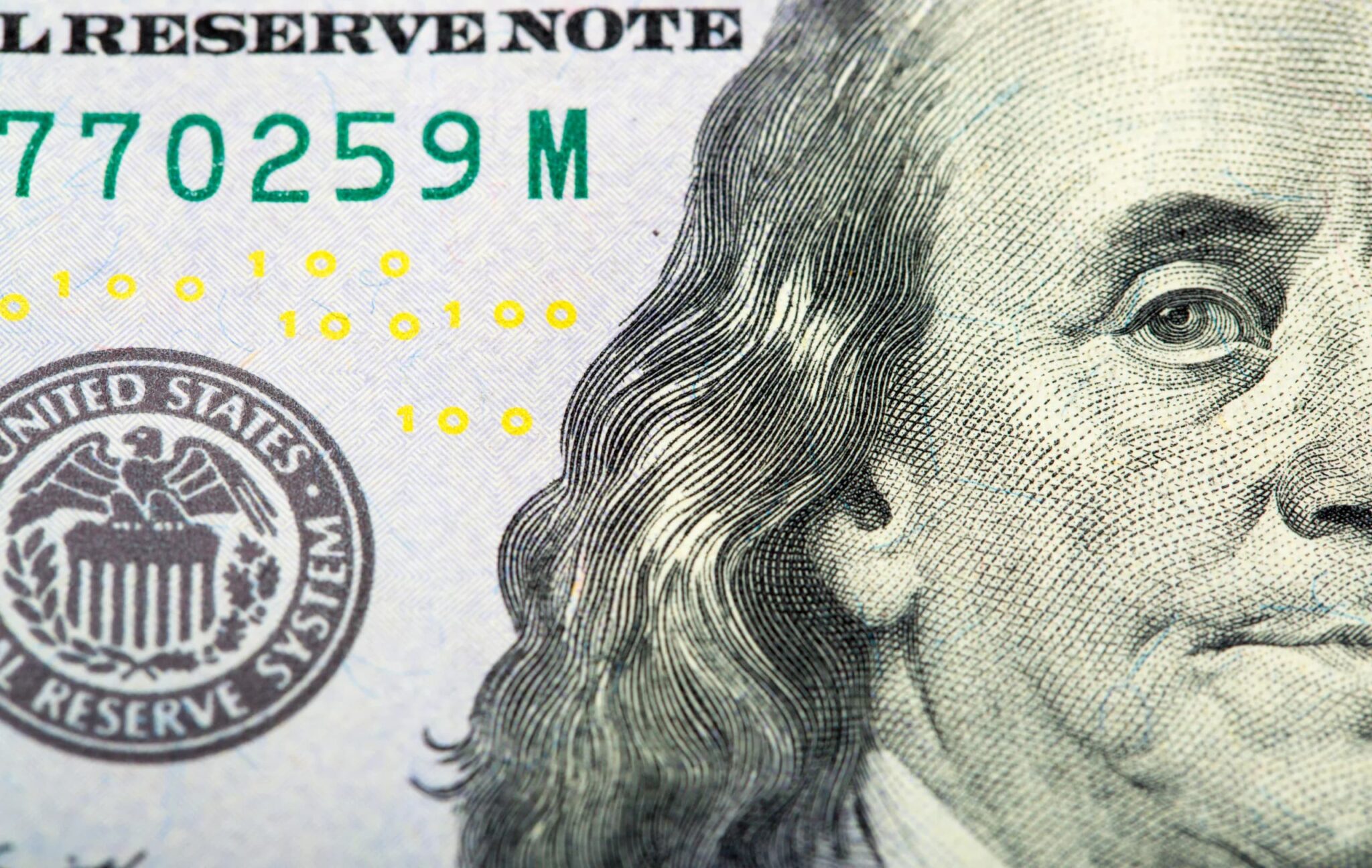 Close-up of a U.S. dollar bill showing part of Benjamin Franklin’s face and the Federal Reserve seal.